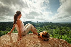 A young woman with a backpack is looking at the ruins of an ancient Maya city Tikal. Guatemala